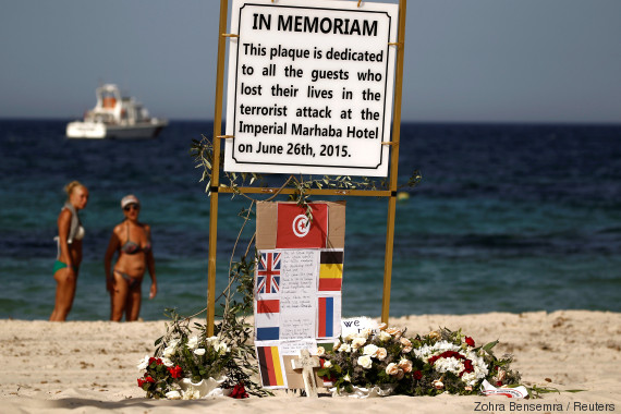 Tourists stand near a plaque dedicated to victims on the beach of the Imperial Marhaba resort, on the first anniversary of an attack by a gunman at the hotel in Sousse